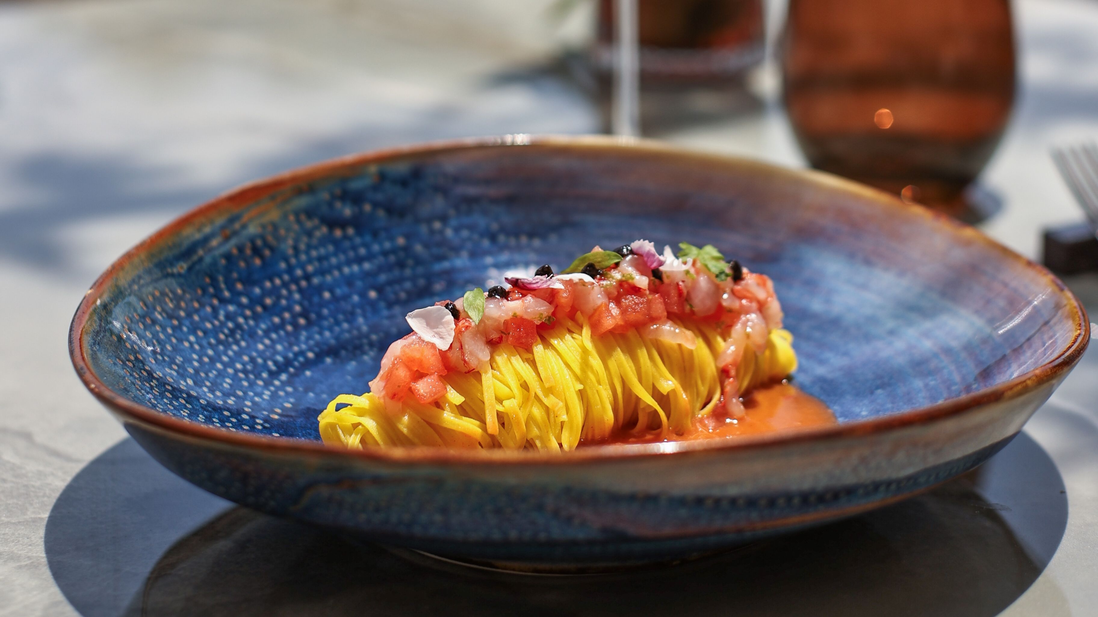 Fresh tagliolino pasta with red prawn in a blue ceramic bowl